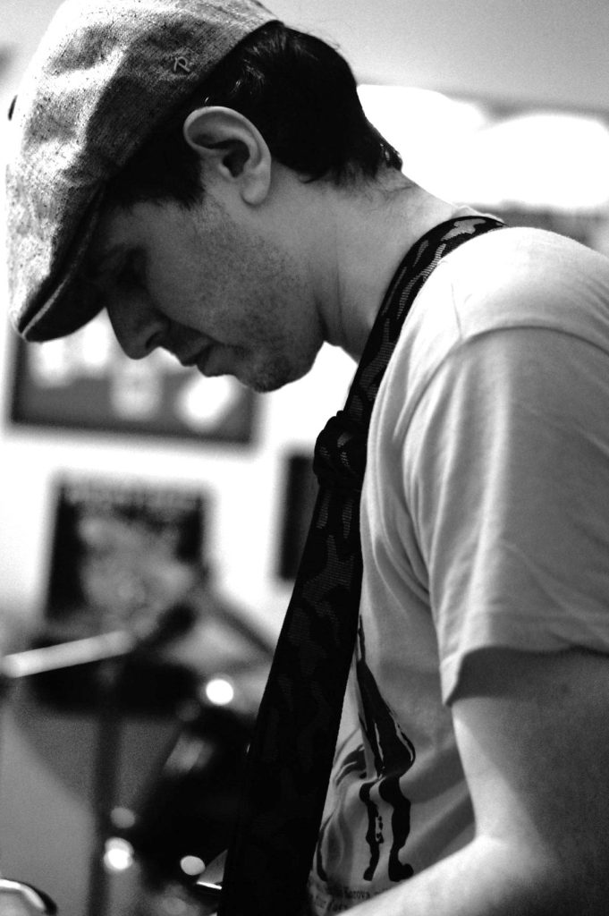 Portrait en noir et blanc de Sylvain Peter, coach pour Guitar Reboot, concentré en train de jouer de la guitare.